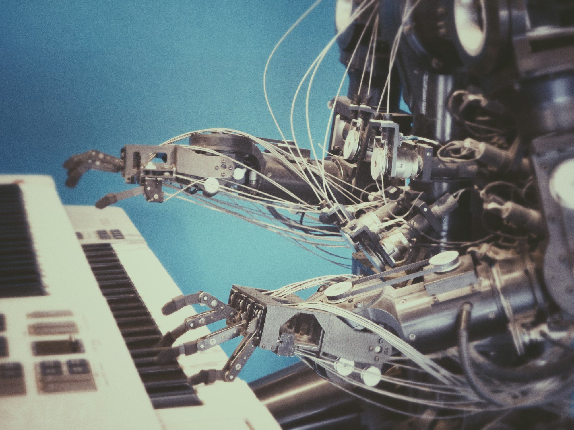 A white robot hand on the keys of a piano
