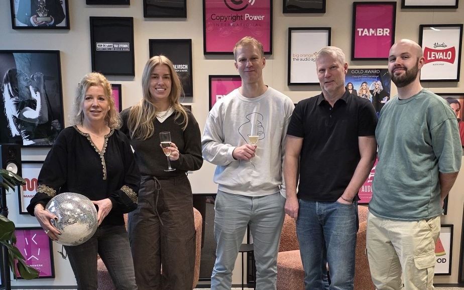 Daan Herweg viert de signing met het team van CPI voor de wand met klantlogo's op kantoor